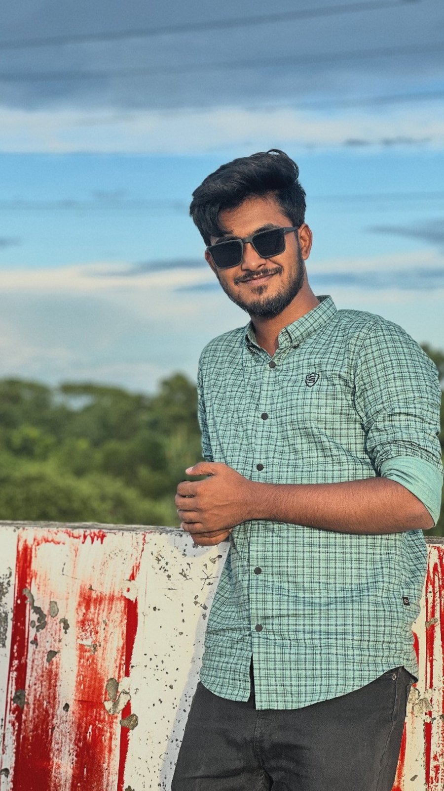 Nayem in a green check shirt and sunglasses on a rooftop